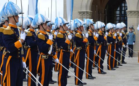 Guardie in uniforme colorata con spade in parata.