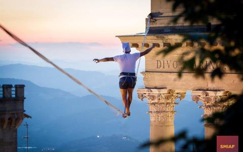 Equilibrista su fune tra edifici storici al tramonto.